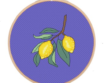 May include: A purple embroidery hoop with a cross-stitch design of a lemon branch with two yellow lemons and green leaves.