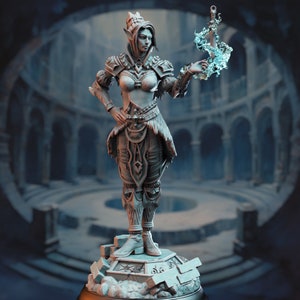 Puede incluir: Una figura en miniatura pintada de blanco de una guerrera elfa femenina sosteniendo una espada azul brillante. La elfa lleva armadura y una corona. La figura está de pie sobre una base de piedra.