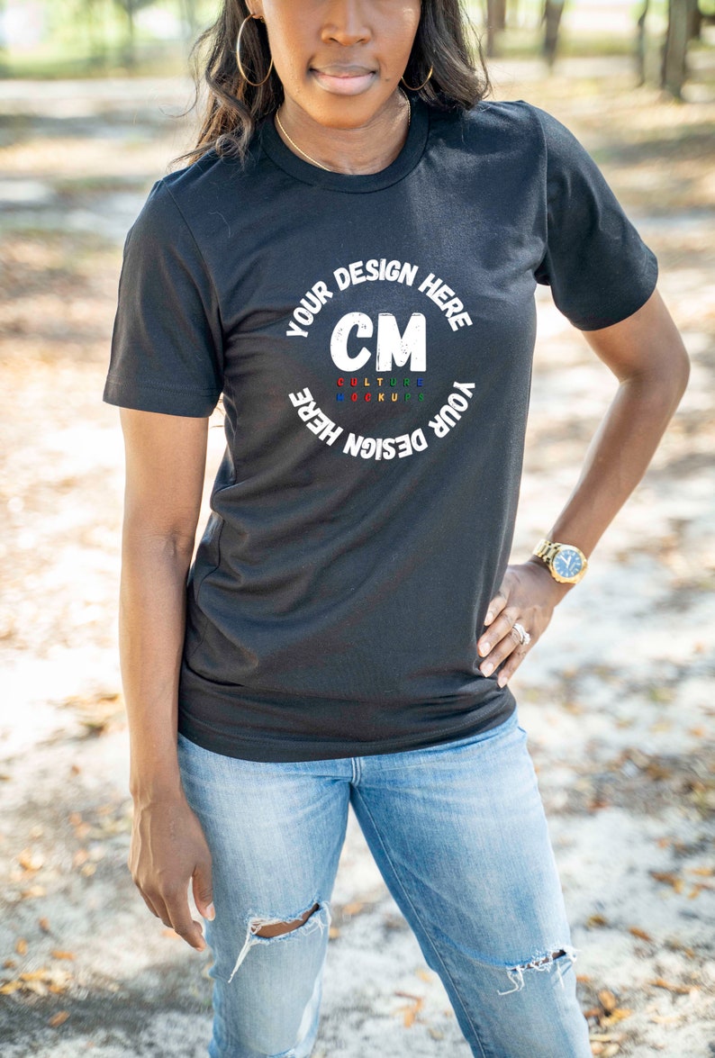 May include: A black t-shirt with a white circle design that says "Your Design Here" and "CM" in the center. The letters "CM" are in red, yellow, green, and blue. The text "Culture Mockups" is written in smaller letters below the "CM".