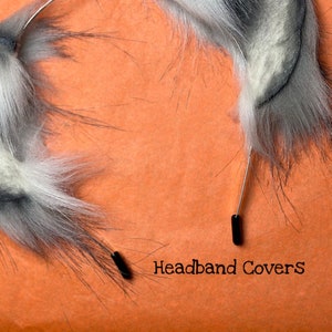 May include: A pair of gray and white faux fur headband covers with black plastic clips. The text "Headband Covers" is printed on a bright orange surface.