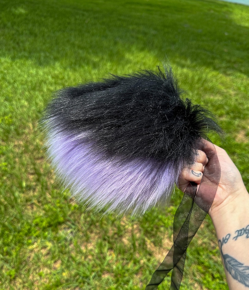 May include: A black and lavender faux fur tail with a black ribbon attached.