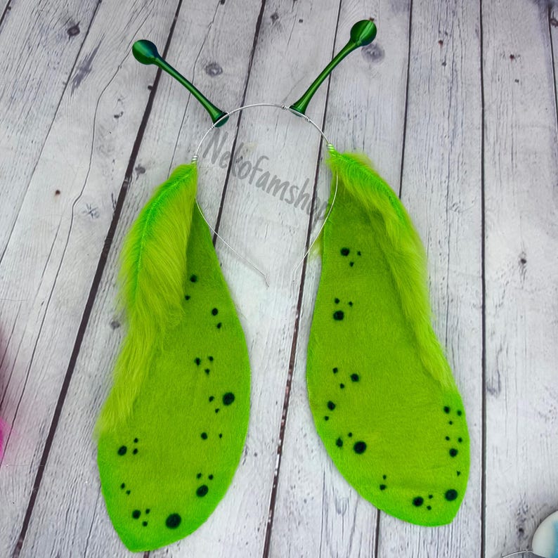 May include: Green felt butterfly wings with black spots and green feathers attached to a silver headband with green antennae.
