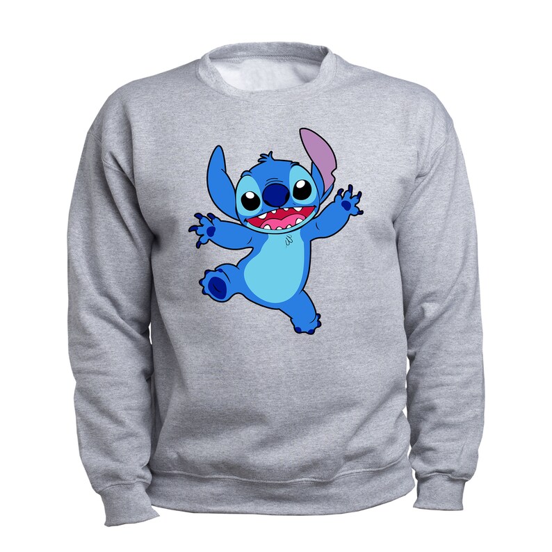 Puede incluir: Una sudadera gris con un personaje de dibujos animados azul de Stitch de la pel&iacute;cula de Disney Lilo & Stitch. Stitch est&aacute; sonriendo y tiene los brazos extendidos.