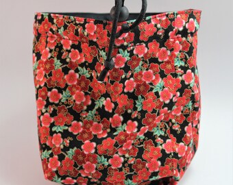 Pode incluir: Uma bolsa de cordão preto com um padrão floral vermelho e dourado. A bolsa é feita de tecido e tem um fecho de cordão preto.