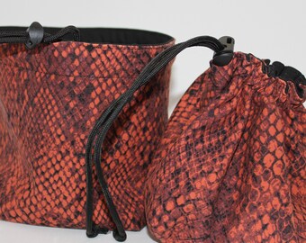 May include: Two drawstring bags with a snakeskin pattern in shades of orange and black. The bags are made of fabric and have black drawstrings.