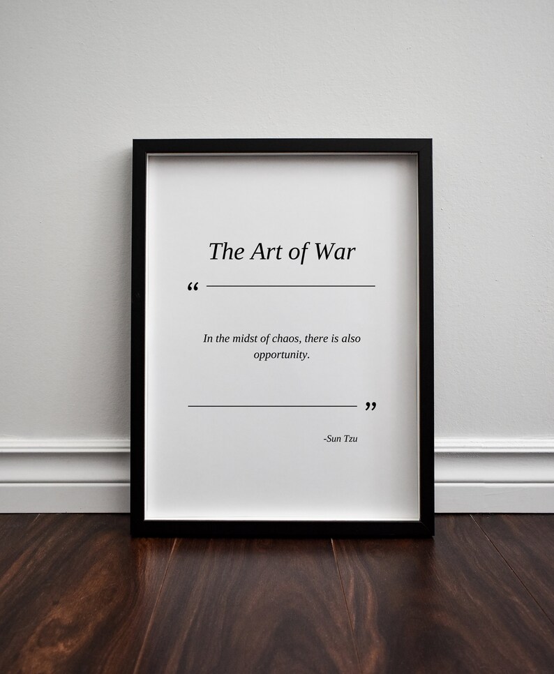 May include: A black framed print with a white background and the text "The Art of War" in black. The quote "In the midst of chaos, there is also opportunity." is printed below the title, followed by the author's name, "Sun Tzu".