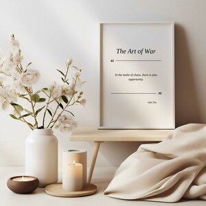 May include: A white framed print with the text "The Art of War" and a quote by Sun Tzu: "In the midst of chaos, there is also opportunity."