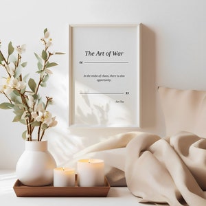 May include: A white framed print with the text "The Art of War" and a quote from Sun Tzu: "In the midst of chaos, there is also opportunity."