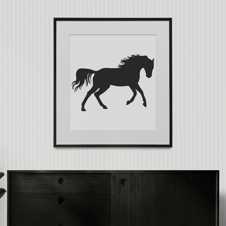 May include: A square wall art piece featuring a black silhouette of a horse in motion against a plain white background, enclosed within a thin black frame. The horse is depicted in profile, facing right, with its mane and tail flowing behind it.