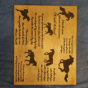 May include: A rectangular light-colored wooden plaque featuring dark brown silhouettes of horses and inspirational quotes about horses. The text includes sayings attributed to Winston Churchill and John Lyons, arranged alongside various horse figures.