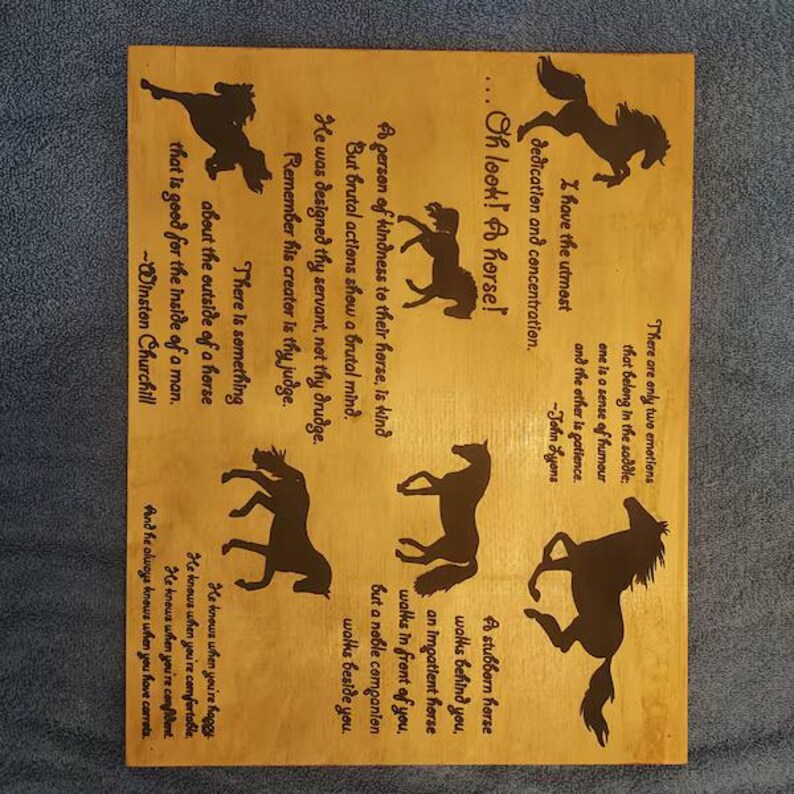 May include: A rectangular light-colored wooden plaque featuring dark brown silhouettes of horses and inspirational quotes about horses. The text includes sayings attributed to Winston Churchill and John Lyons, arranged alongside various horse figures.