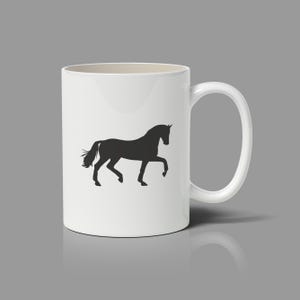 May include: A white ceramic mug featuring a black silhouette of a horse in a trotting stance. The mug has a smooth, cylindrical body with a curved handle on the right side. The design is centered on the front of the mug, showcasing the horse.