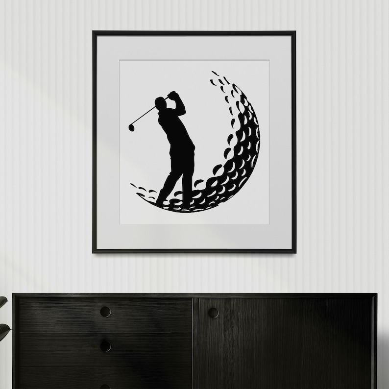 May include: Black and white silhouette of a golfer swinging a club, with a golf ball in the background. The image is framed in a black frame.