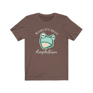 May include: A brown t-shirt with a white graphic of a cartoon frog and the text "WORLD'S BEST AMPHIBIAN".