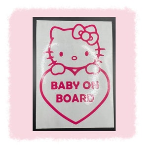 May include: A pink and white "Baby on Board" car decal featuring a cartoon cat design. The cat is outlined in pink, with a pink bow and a heart-shaped graphic that contains the text "BABY ON BOARD".
