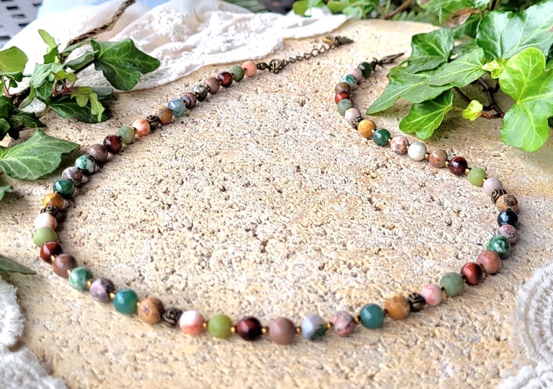 Peut inclure: Un collier de pierres pr&eacute;cieuses multicolores avec un fermoir en laiton. Le collier pr&eacute;sente une vari&eacute;t&eacute; de pierres, notamment du vert, du brun, du rouge et du rose.