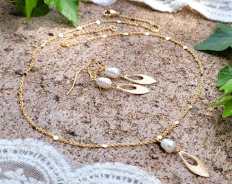 May include: A gold necklace and earrings set with a delicate chain and leaf-shaped pendants accented with white pearls.