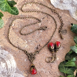 Pode incluir: Um conjunto de colar e brincos de bronze com contas de vidro vermelho em forma de bagas. O colar apresenta um delicado pingente de borboleta e uma corrente com fecho de lagosta. Os brincos s&atilde;o de estilo pendente com um aro pequeno.