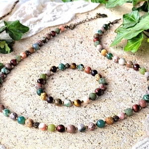 Peut inclure: Un ensemble de collier et de bracelet en pierres pr&eacute;cieuses multicolores. Le collier et le bracelet sont faits de diff&eacute;rentes pierres, notamment du rouge, du vert, du brun et du blanc. Le collier est plus long que le bracelet.