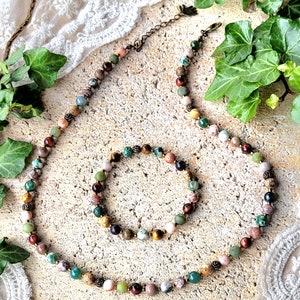Peut inclure: Un ensemble de collier et de bracelet en pierres pr&eacute;cieuses multicolores. Le collier et le bracelet sont faits de diff&eacute;rentes pierres, notamment du vert, du brun, du rouge et du rose. Le collier a un fermoir en laiton.