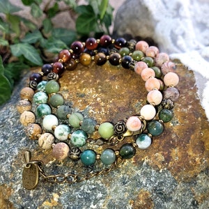 May include: Multi-colored gemstone bracelet with a brass clasp and a charm that says "Made with Love".