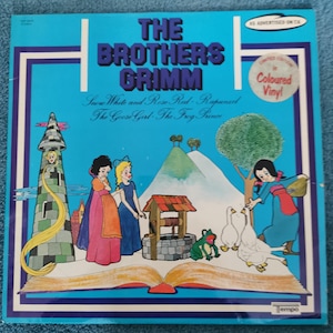 May include: A vintage vinyl record album titled "The Brothers Grimm" with a colourful illustration. The cover features scenes from fairy tales like Snow White, Rapunzel, and The Frog Prince, with a blue background and a "Coloured Vinyl" sticker.