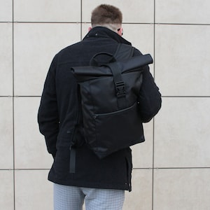 May include: A black roll-top backpack with a single buckle closure and a small zippered pocket on the front.