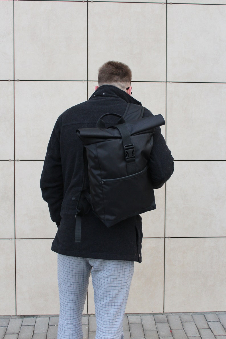 May include: A black roll-top backpack with a single buckle closure and a small zippered pocket on the front.