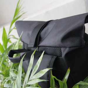 May include: A black backpack with a flap top and a mesh pocket. The backpack is made of a durable, water-resistant material.
