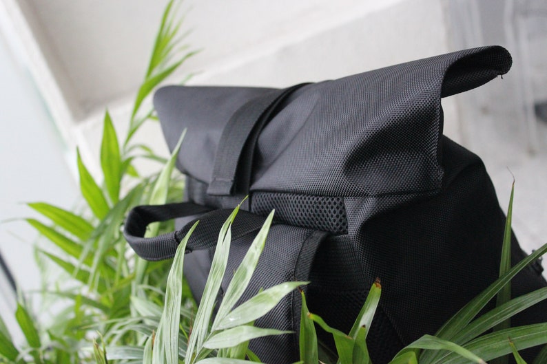 May include: A black backpack with a flap top and a mesh pocket. The backpack is made of a durable, water-resistant material.