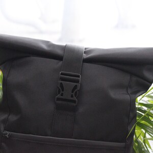 May include: Black roll-top backpack with a black adjustable strap and buckle closure.