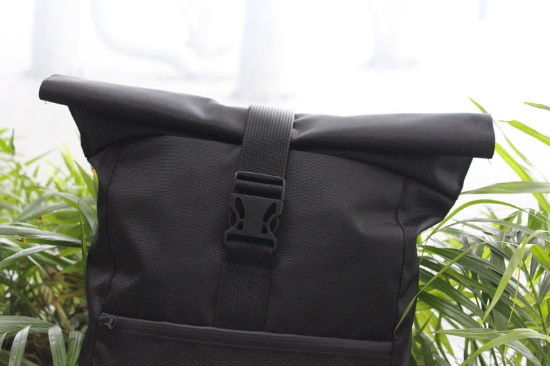 May include: Black roll-top backpack with a black adjustable strap and buckle closure.