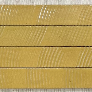 May include: Four yellow ceramic tiles with a textured surface. The tiles have a subtle, wavy pattern.