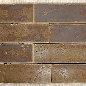 Könnte beinhalten: Nahaufnahme von vier braunen Keramikfliesen mit einer strukturierten Oberfläche. Die Fliesen haben eine gefleckte braune und graue Farbe mit einem dezenten Muster.