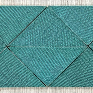 Puede incluir: Seis azulejos triangulares de color azul verdoso con un patrón de veta de madera. Los azulejos están dispuestos en forma hexagonal.