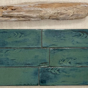 Pode incluir: Quatro azulejos de cerâmica verde com um padrão de grão de madeira. Os azulejos são dispostos em um padrão escalonado.