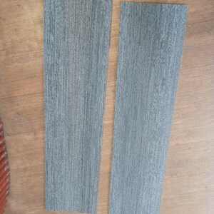 May include: Two rectangular pieces of gray wood-look vinyl flooring.