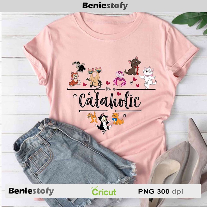May include: A light pink t-shirt with the text "I'm a Cataholic" and various cartoon cat illustrations. The shirt is paired with denim shorts and a pair of high heels. The image also includes the brand name "BenieStofy" and "Cricut".