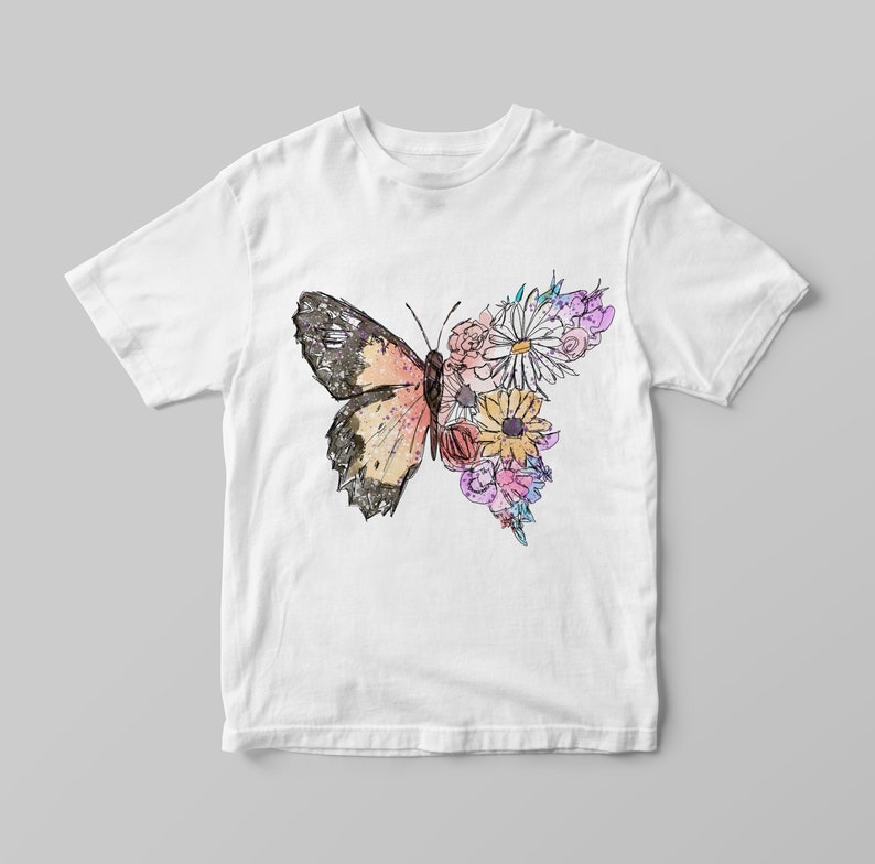 May include: White t-shirt with a colorful butterfly and floral design. The butterfly is outlined in black and has pink, orange, and yellow wings. The flowers are pink, yellow, and purple.