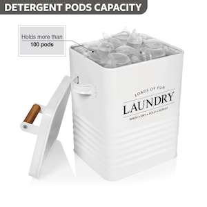 May include: White metal laundry pod storage container with a lid and a wooden handle. The container has a black and white label that says "Loads of Fun Laundry Wash Dry Fold Repeat". The container is filled with laundry pods.