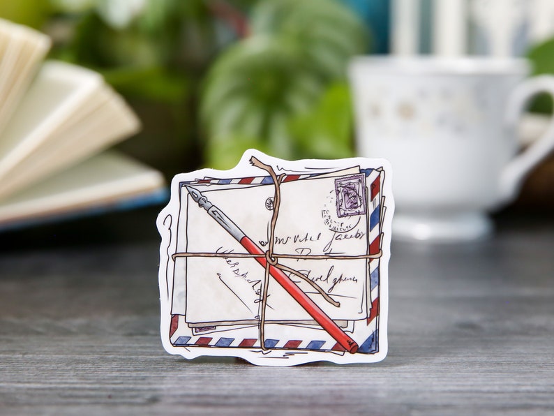 May include: A stack of vintage-style envelopes tied with twine and a red pen, with a blue and red striped pattern on the edges. The envelopes have handwritten text and a stamp.