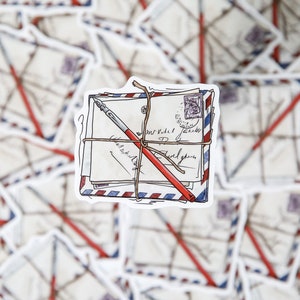 May include: A stack of vintage envelopes tied with twine and a red pen, with handwritten text on the envelopes. The envelopes have a blue and red striped pattern.