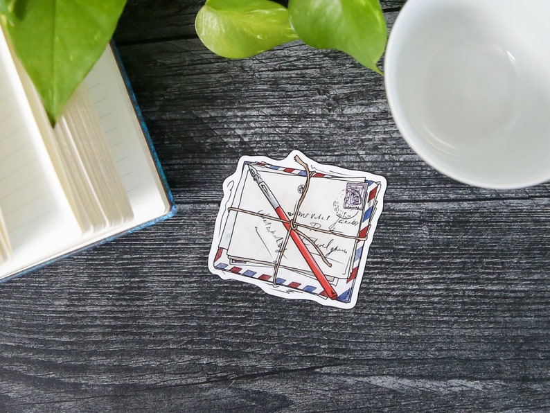 May include: A sticker of a stack of envelopes tied with twine and a red pen. The envelopes have blue and red stripes and a stamp with a picture of a person on it.