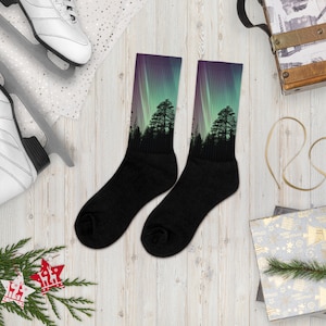 May include: A pair of black socks with a colorful aurora borealis and forest silhouette design. The socks are made of a soft, comfortable material and are perfect for everyday wear.