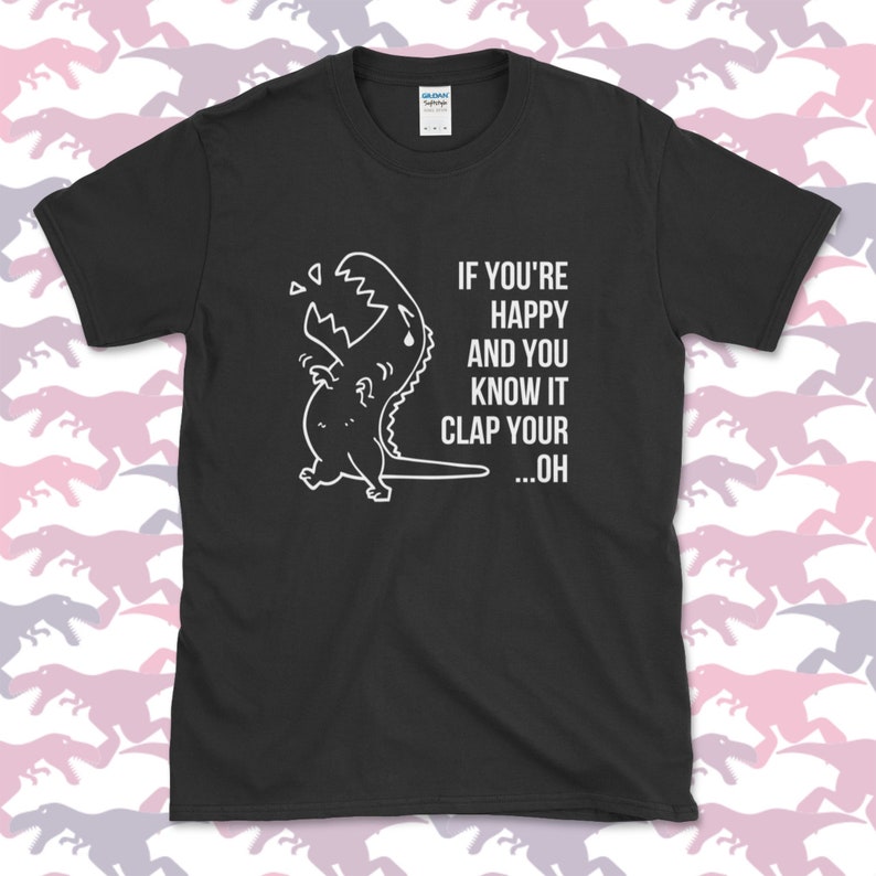 Peut inclure: T-shirt noir avec un dinosaure de dessin anim&eacute; blanc et le texte "Si tu es heureux et que tu le sais, applaudis...oh".