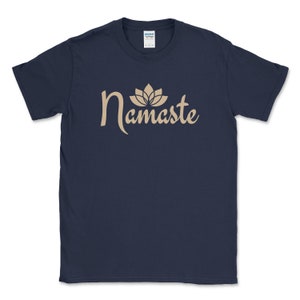 K&ouml;nnte beinhalten: Marineblaues T-Shirt mit dem Wort "Namaste" in beigefarbener Schrift, gekr&ouml;nt von einem Lotusbl&uuml;ten-Design. Das kurz&auml;rmelige Rundhals-T-Shirt ist perfekt f&uuml;r den Alltag.