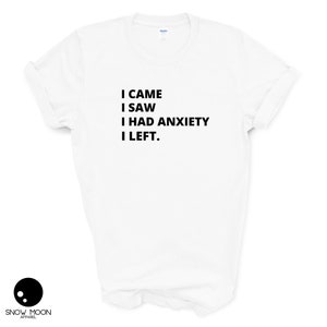 May include: White t-shirt with black text that reads "I came I saw I had anxiety I left."