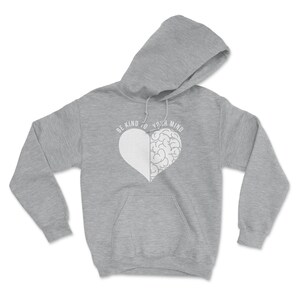 May include: A gray hooded sweatshirt with a white heart design. The heart is split in half, with one side being a brain and the other side being a blank space. The text "BE KIND TO YOUR MIND" is printed around the heart.
