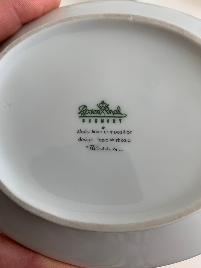 K&ouml;nnte beinhalten: Eine wei&szlig;e Keramiksch&uuml;ssel mit einem gr&uuml;nen Logo, das "Rosenthal Germany" lautet, und dem Text "studio-linie: composition design: Tapio Wirkkala Wirkkala".