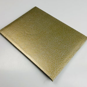 May include: A gold-coloured notebook with a textured cover.